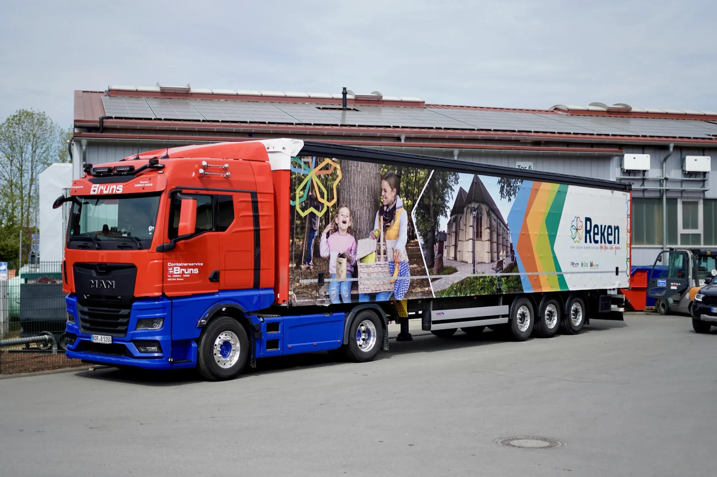 MAN-Sattelzug von Bruns Transporte mit bedrucktem Planenauflieger vor einer Halle
