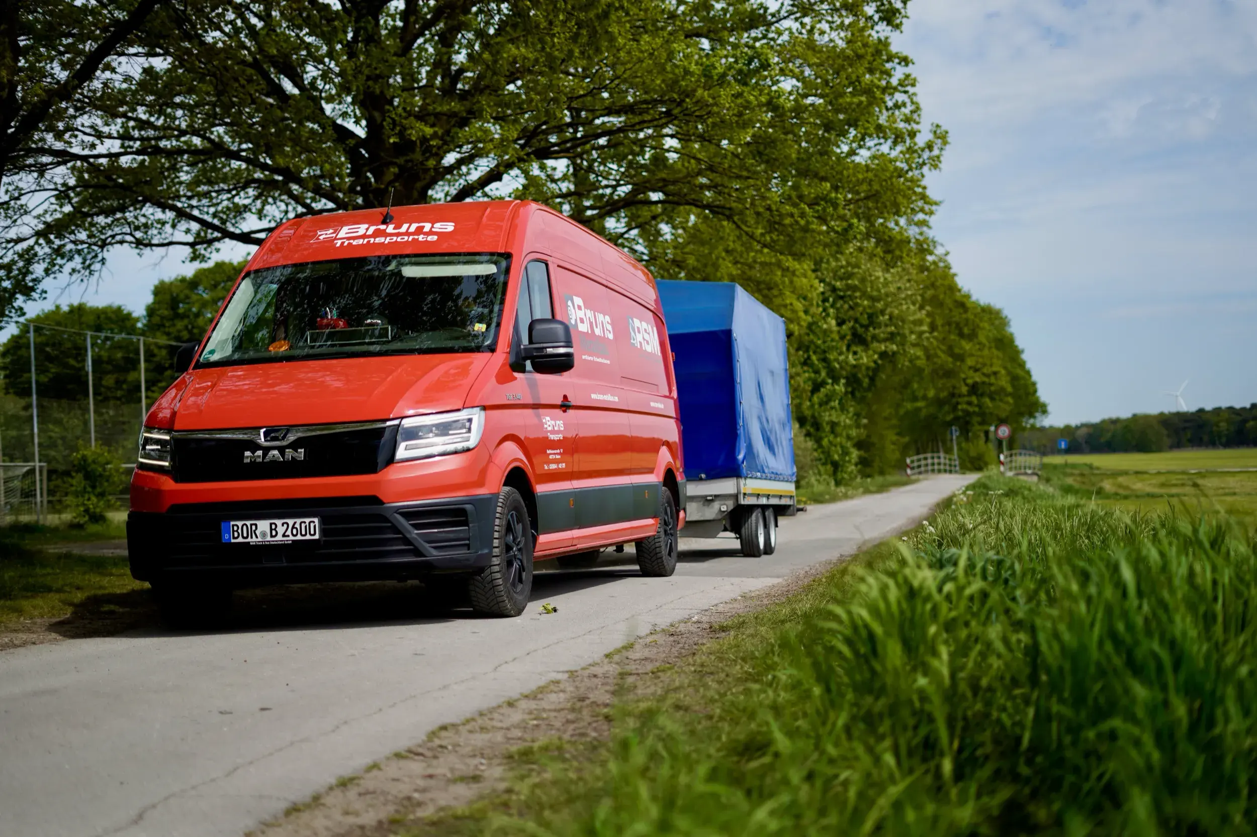 Roter MAN-Transporter von Bruns Transporte mit Planenanhänger auf einer Landstraße